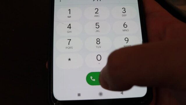 Close-up hand dialing 911 on a mobile phone in the dark to contact the police during an emergency or a crime