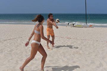 couple on the beach playing doubles volleyball