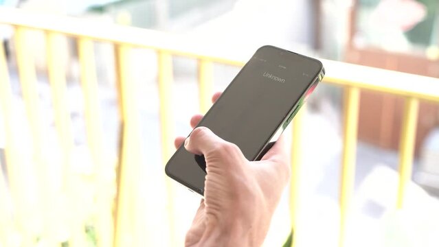 Fraud or fraudulent schemes. Close-up of a male hand holding a phone with an unexpected incoming call from an unknown