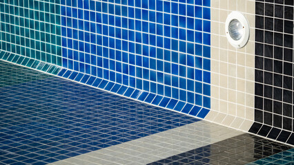White LED light in a swimming pool without water on a tile wall and mixed color floor pattern....