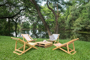 Relax wooden deckchair and table on green grass yard by pond