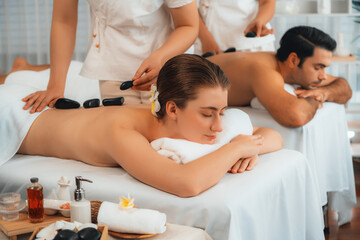 Hot stone massage at spa salon in luxury resort with day light serenity ambient, blissful couple...