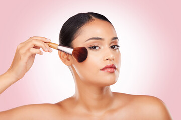 Obraz na płótnie Canvas Cosmetics, makeup brush and portrait of woman in studio for glamour, glow or face routine. Beauty, self care and young Indian female model with facial cosmetology product isolated by pink background.