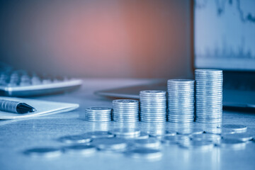 Up stack money coin with laptop computer and calculator in the background, Business and Financial concept with blue filter. 