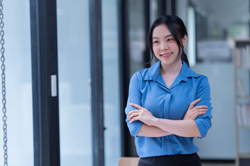 Sharing good business news. Attractive young businesswoman talking on the mobile phone and smiling while sitting at her working place in office and looking at laptop PC.