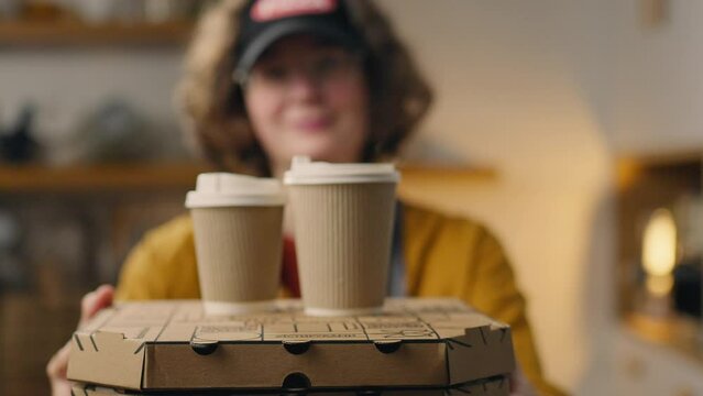 A young pizza master operator holds in his hands a ready-made order of pizza cardboard boxes. Delivery of the order hot pizza in boxes and coffee in paper cups. Courier food delivery, takeaway food