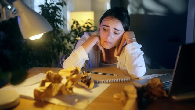 Portrait of exhausted young woman with head on her hands feeling upset while take a break at home Tired female with failed ideas creative block or lack of inspiration indoors
