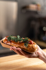 Woman holds fresh hot dog with sauce in hands. Street food, fast food