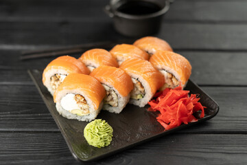 Top view of sushi with salmon and smoked eel on stone plate on wooden background served with wasabi and ginger