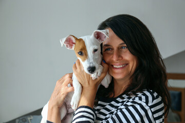Portrait of a beautiful brunette mid adult woman playing with her adorable jack russell terrier...