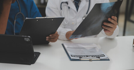 Fototapeta Focused mature male doctor and female nurse look at tablet screen discuss anamnesis together. Concentrated diverse medical professionals use pad device, engaged in team thinking in hospital. obraz