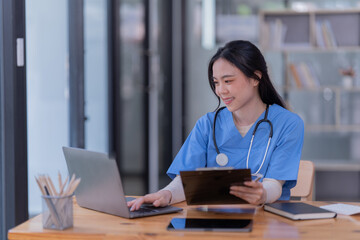 Fototapeta premium Portrait of Asian female doctor working on the desk and smiling