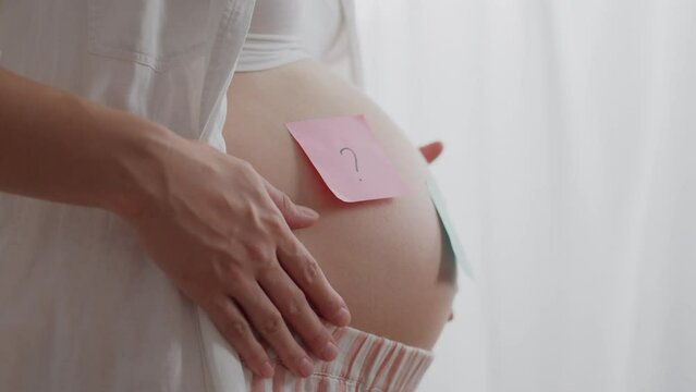 Expecting. Mom of expectant baby in light colored clothes guessing the sex of the baby in daylight. Cute girl doesn't want to know the sex of the baby advanced methods of newborn care, mom is waiting