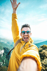 Young hiker man taking vertical selfie portrait on the top of mountain - Happy guy smiling at...