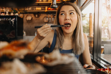 Happy asian woman eating korean grilled buffet in the restaurant.
