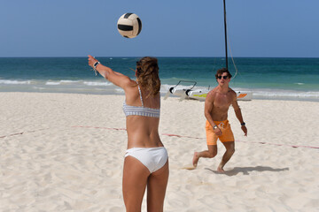 couple playing coed volleyball on the beach