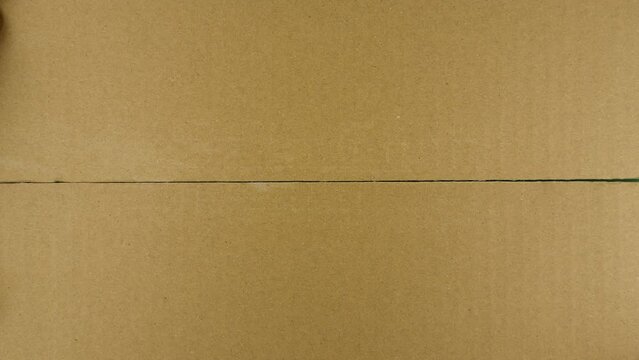 Unpacking carton box with chromakey inside. Hand tears off adhesive tape from a cardboard box, view from the top
