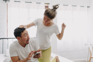 Fototapeta premium Asian woman angry on man who keep chatting on the phone. Funny couple fight. High quality photo