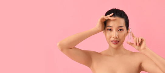 Obraz premium Beautiful Asian woman holding ampule on pink background with space for text. Skin care concept