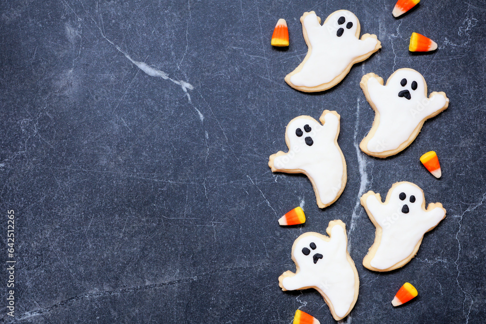 Poster halloween ghost cookie side border. top down view on a dark stone background with copy space.