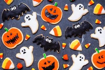 Halloween cookie background. Above view on dark stone. Ghosts, bats, jack o lanterns and candy corn.