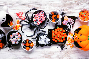 Halloween trick or treat candy table scene. A variety of spooky sweets. Overhead view on a white wood background with copy space. - Powered by Adobe