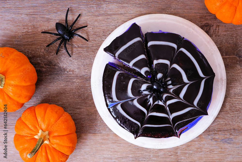 Poster halloween spider web cake. top down view table scene over a wooden background.