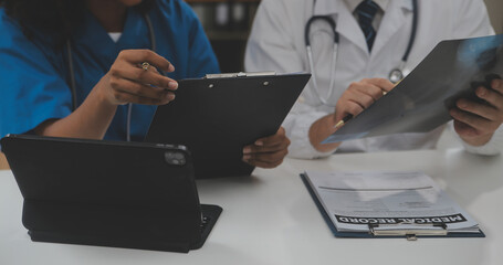 Focused mature male doctor and female nurse look at tablet screen discuss anamnesis together. Concentrated diverse medical professionals use pad device, engaged in team thinking in hospital. - obrazy, fototapety, plakaty