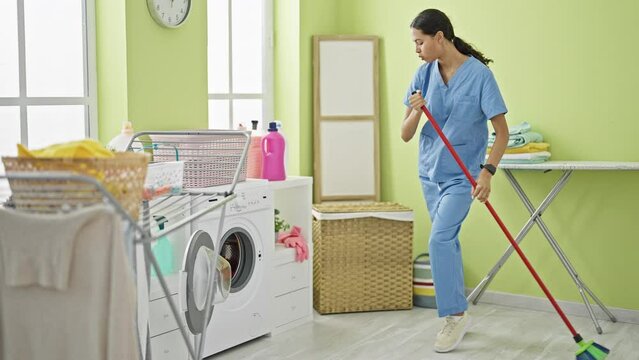African american woman professional cleaner looking watch cleaning floor at laundry room