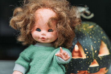 Close-up of carved pumpkin with old, vintage doll. Halloween decoration concept