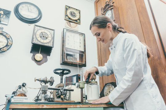 Woman watchmaker cleaning clockwork of a watch in her workshop
