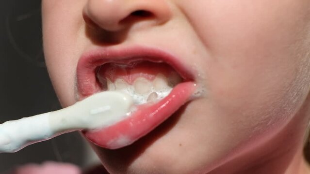 Happy smiling little girl brush teeth using ultrasonic electric toothbrush in bathroom at home. Oral hygiene, dental and gum health, healthy teeth. Daily life and routine