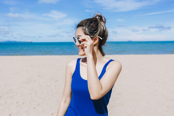 Happy asian woman in blue dress walking on the beach in Pattaya Thailand.
