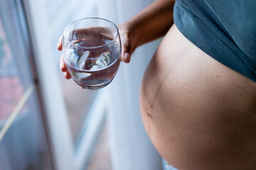Drinking water during pregnancy, woman holding a glass of water, body hydration