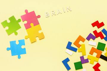 Word BRAIN with puzzle pieces and blocks on yellow background. Logic concept