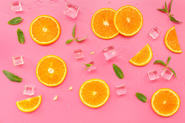 Orange slices with water drops, mint and ice cubes on pink background
