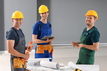 Team of male builders working in room