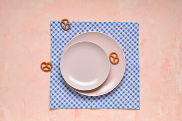 Empty plates, pretzels and blue checkered napkin on pink table