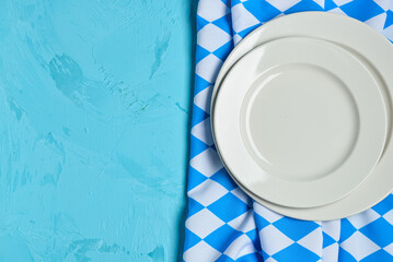 Empty plates and checkered tablecloth on blue background