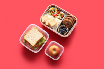 Lunchboxes with different delicious food on red background