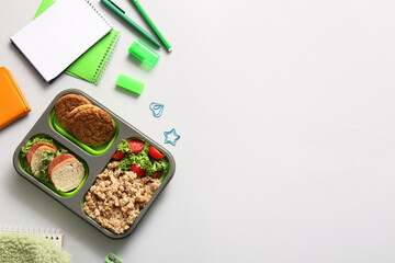 Lunchbox with delicious food and different stationery on white background
