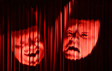 Two theatre masks, one smiling and one frowning, projected on a red curtain. One representing comedy and the other representing tragedy. The curtain is made of red velvet