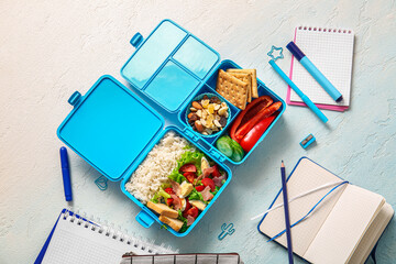 Lunchboxes with delicious food and different stationery on gradient background