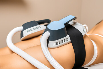 Young womans buttocks receive precise body sculpting treatment with specialized equipment