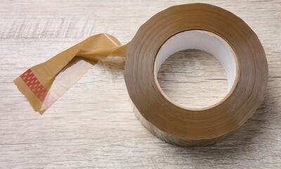 Roll of brown tape on a wooden table, top view