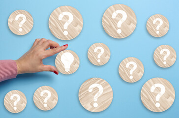 The hand holds a wooden plate with an electric lamp and dice with question marks. The concept of...
