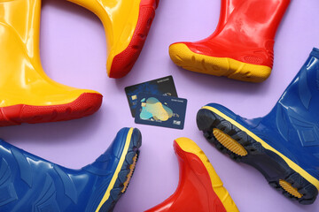 Composition with child's rubber boots and credit cards on lilac background, closeup