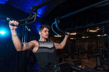 Man performs exercise for back on machine at gym