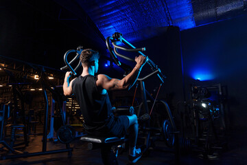 Fototapeta na wymiar Man performs exercise for back on machine at gym