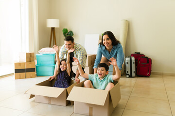 Parents and kids racing on boxes while moving into their new home